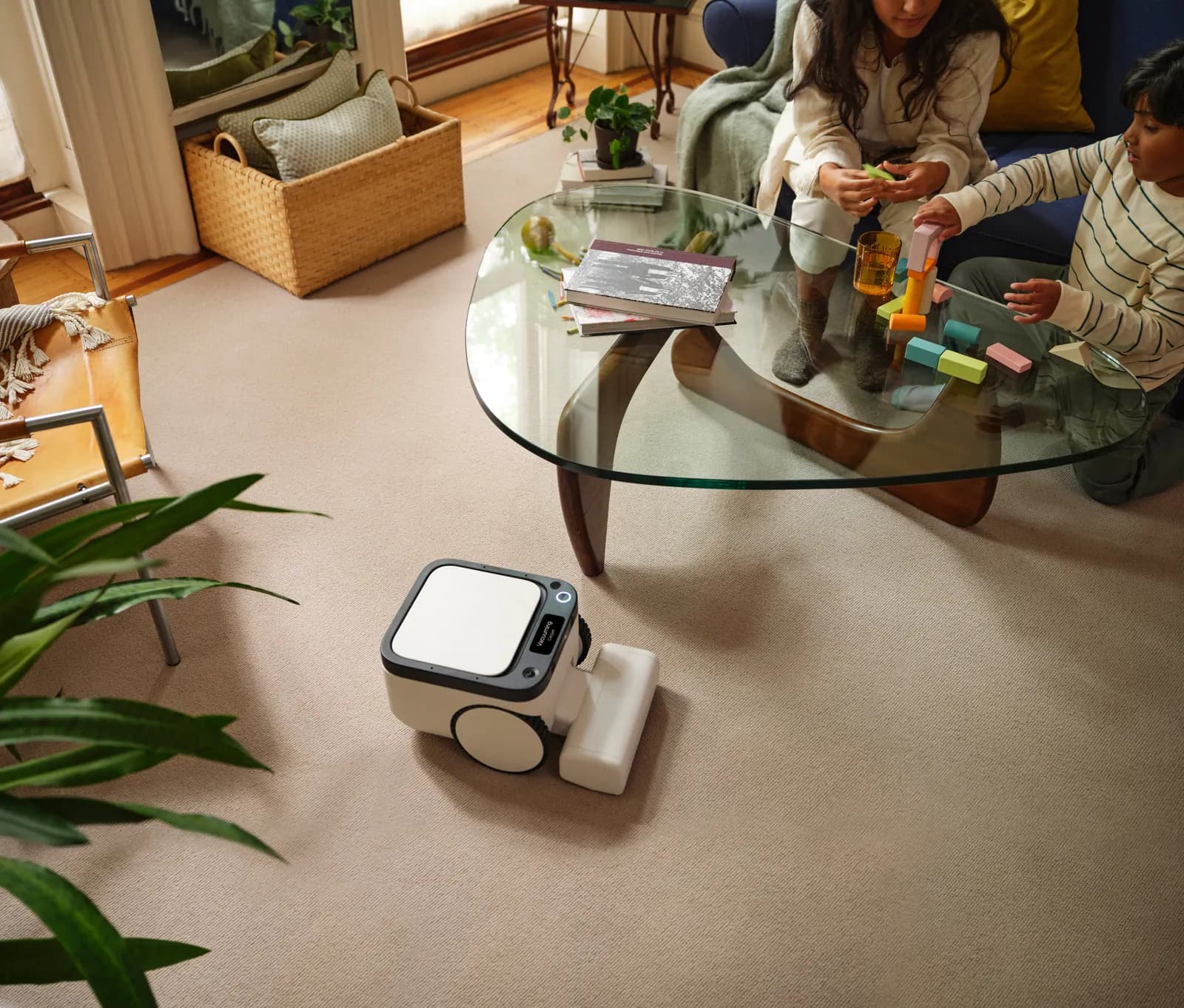A Matic robot cleaning a carpeted living room while two children play nearby