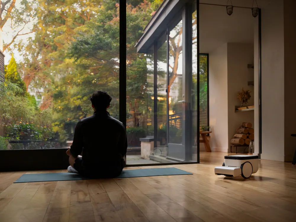 The Matic robot cleaning a room while a person exercises on a mat